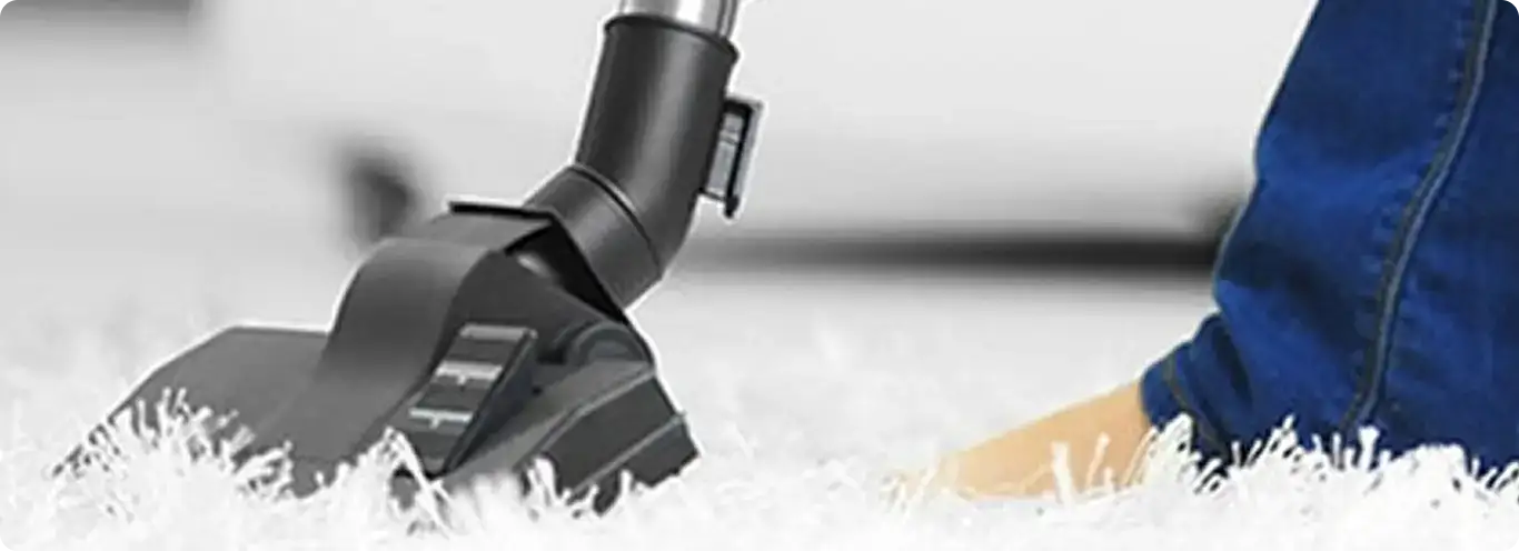 Close-up of a professional vacuuming a white carpet in Hallsville.
